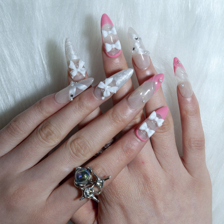 Sweet French tip nails with white bows and crystal accents
