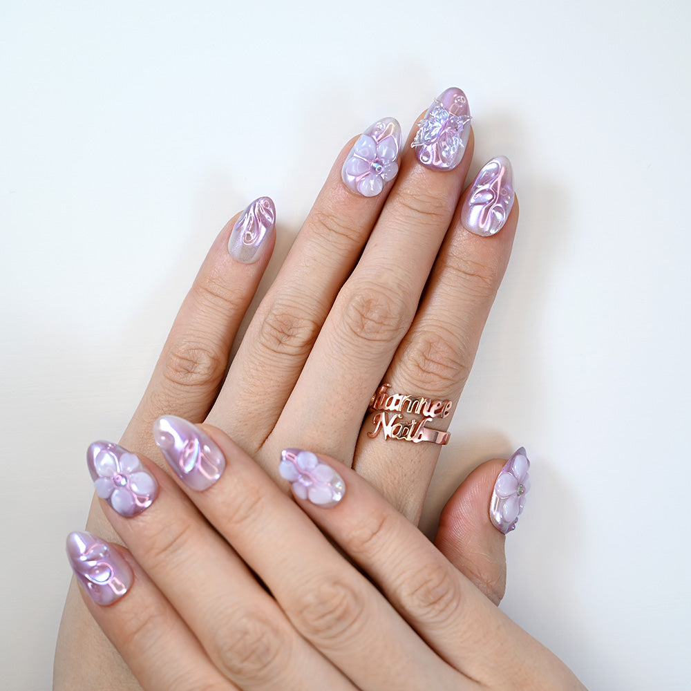 Pastel purple chrome nails with handmade flower art and sparkling gem accents