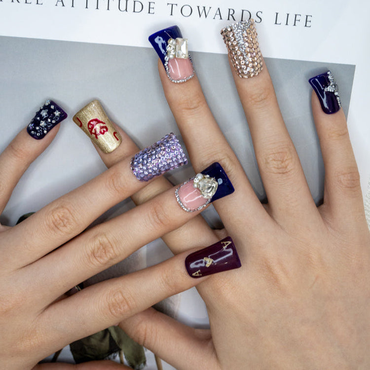 Handmade press-on nails featuring glitter gold lips, purple gems, and crystal details