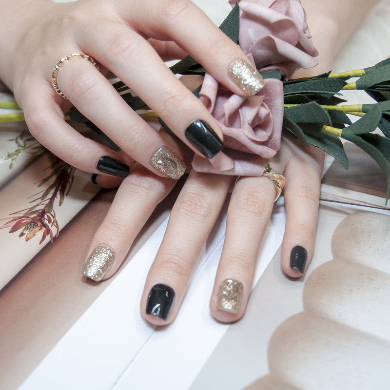 Short square black handmade press-on nails with gold sparkle and transparent embossed design