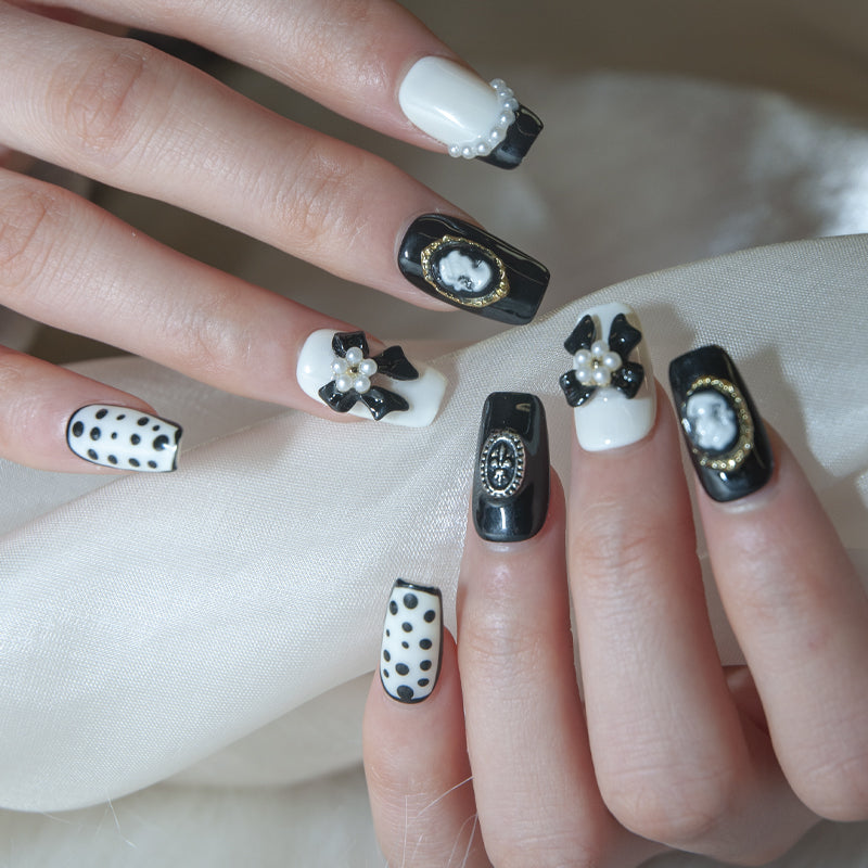 Elegant monochrome nails featuring polka dots, pearls, and retro portrait frames