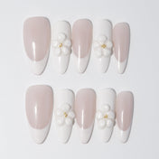 Handmade nude and white French nails featuring delicate floral charms