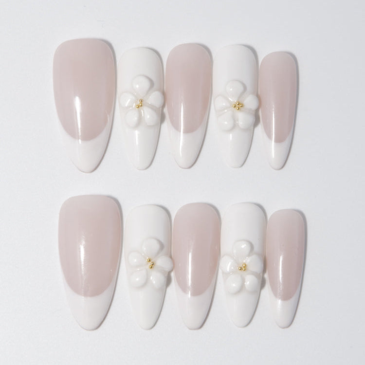 Handmade nude and white French nails featuring delicate floral charms