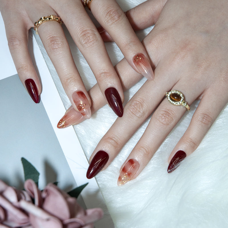 Handmade wine red nails with nude marble effect and shiny gold foil details