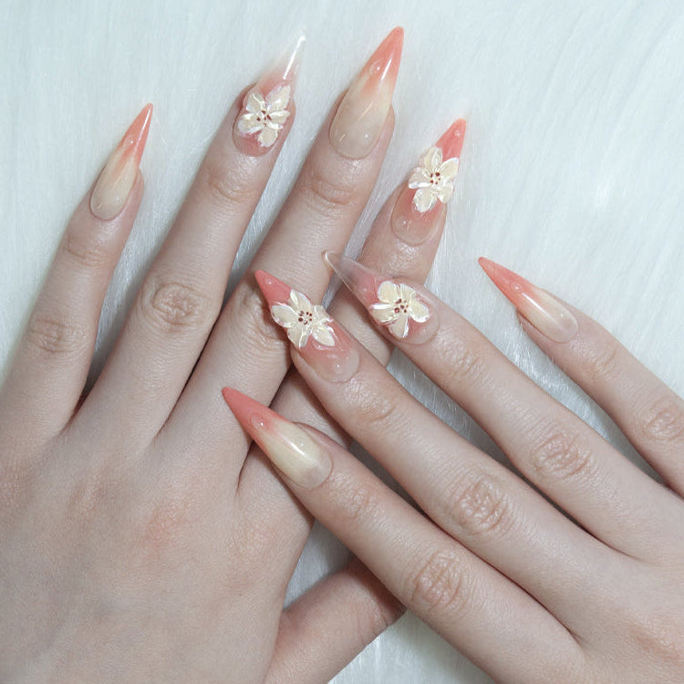 Elegant ombre nails with soft orange-pink tones and raised floral designs