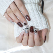 Glossy burgundy nails with silver glitter, pearl charms, and statement stones