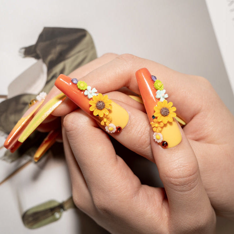 Gradient orange yellow nails with sunflower charms and tiny hearts