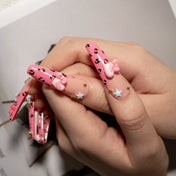 Kawaii style press-on nails with cartoon cat charms, pastel stars, and pink glitter bows