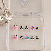 Short silver glitter nails with playful cow pattern and 3D candy accent