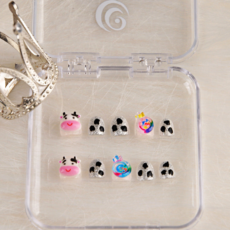 Short silver glitter nails with playful cow pattern and 3D candy accent