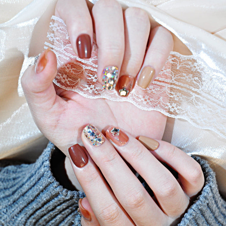 Elegant press-on nails featuring brown marble, glitter mix, and metallic stars