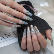 Elegant white to metallic ombre nails with pearl centerpiece and rhinestone accents