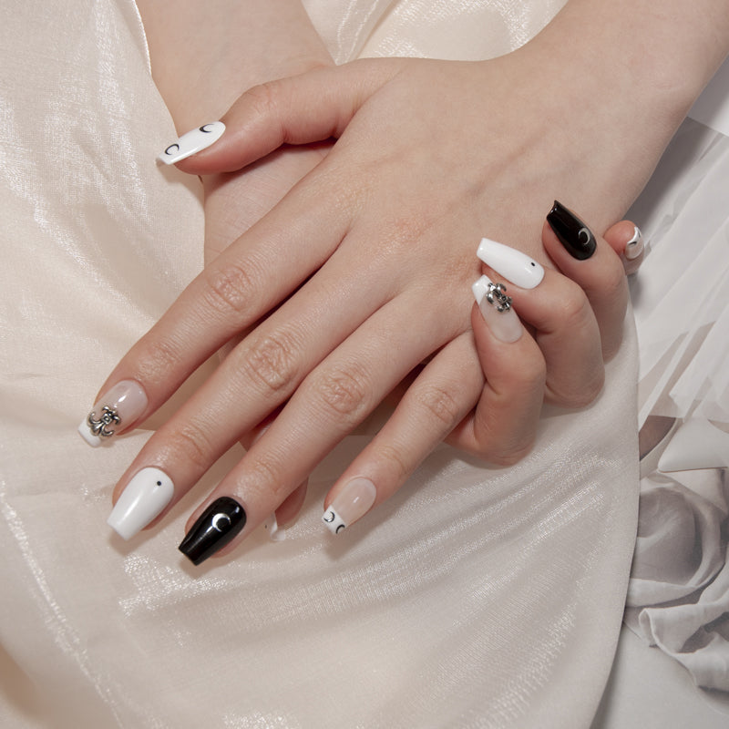 Minimalist black and white press-on nails with crescent moon art and gothic charm