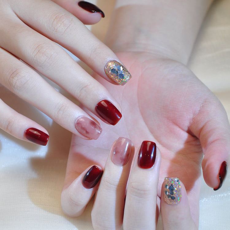 Elegant handmade press-on nails with rich red polish and sparkling gold glitter accent