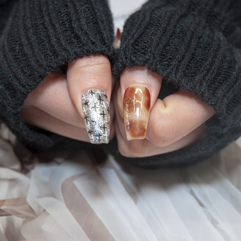 Nude and brown press-on nails with metallic cross nail art