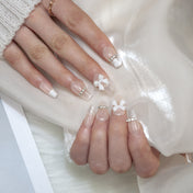 Elegant ivory nails with 3D bow design, rhinestone line, and subtle glitter fade
