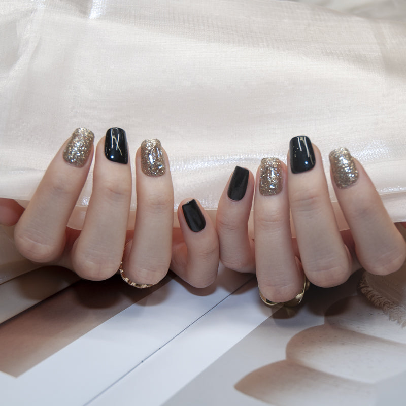 Elegant black nails with gold glitter accent and clear textured detail