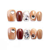 Short brown press-on nails with silver star charms and glitter accents