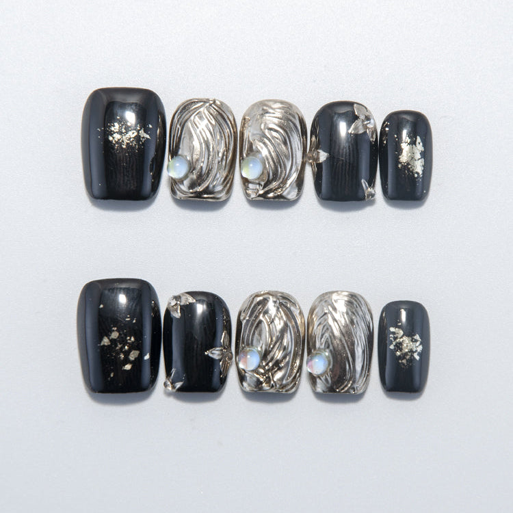 Black and gold press-on nails with 3D swirl texture and pearl gemstone accents