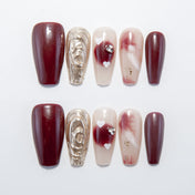 Burgundy press-on nails with gold 3D swirl accent and marble hearts