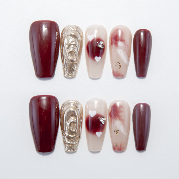 Burgundy press-on nails with gold 3D swirl accent and marble hearts