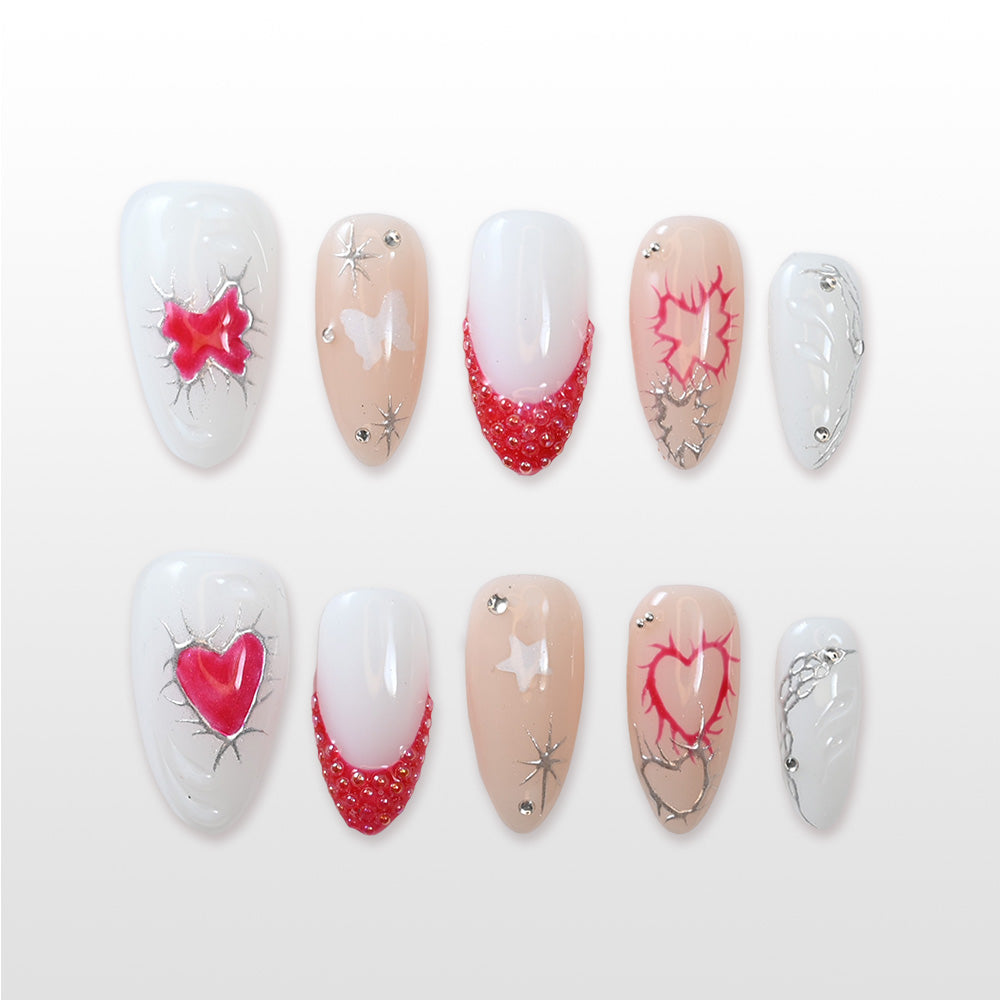 White and nude press-on nails with 3D red heart art, lightning crack design and rhinestone details