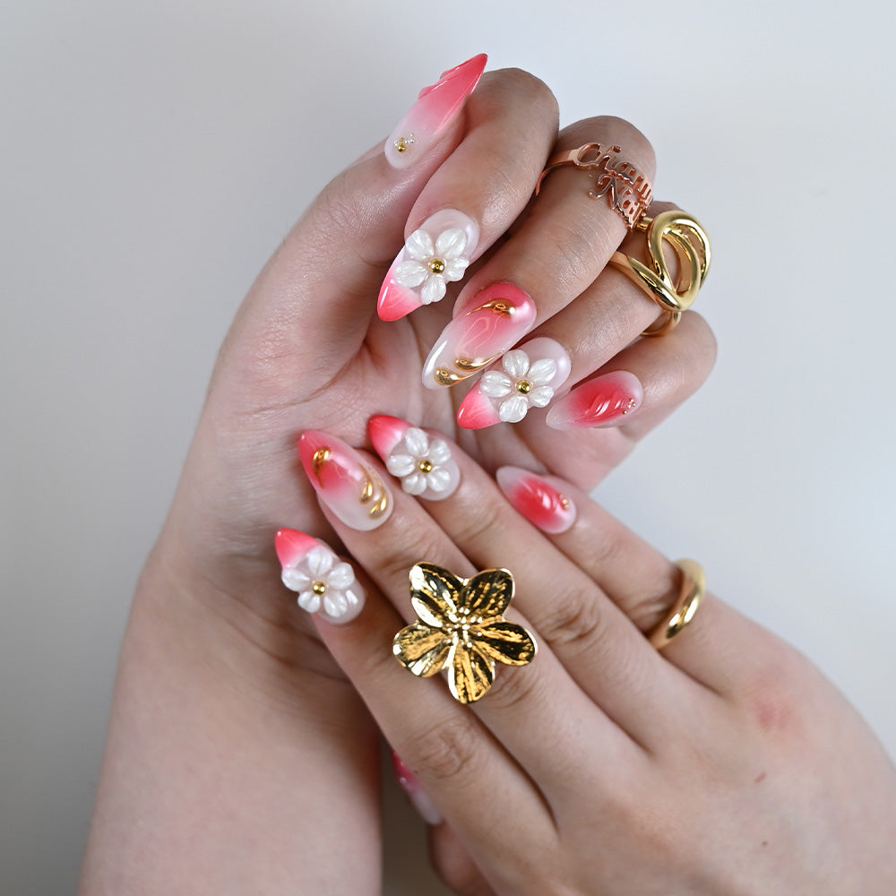 Hand model wearing handmade pink press on nails with sculpted petals and almond shape
