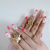  Elegant press on nails with white blossoms, coral pink base, and metallic design details