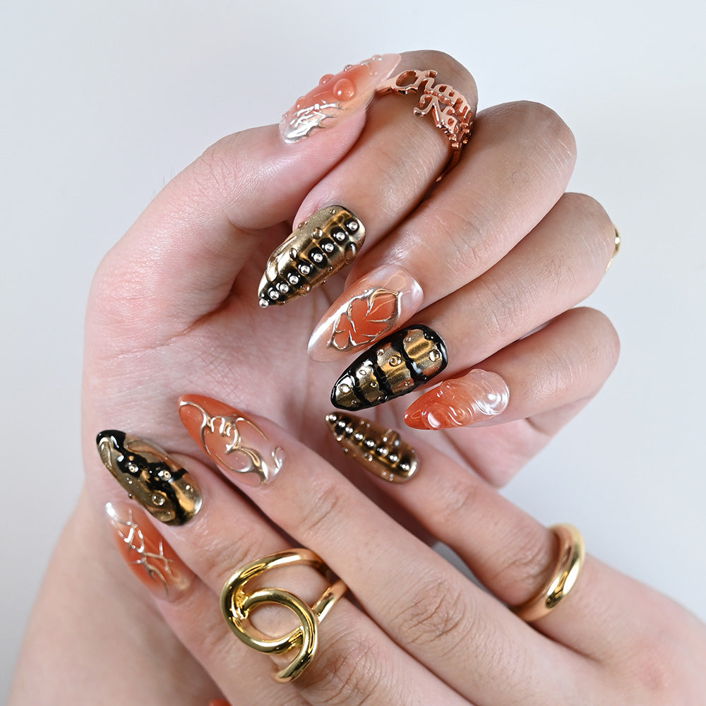 Statement almond nails with punk-style silver studs, transparent layers, and bold accents