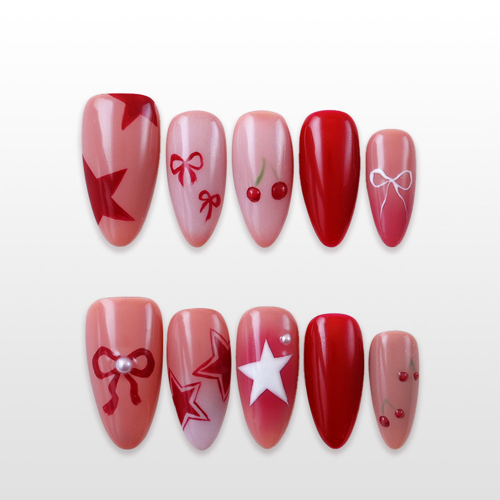 Red and nude press-on nails with cherries, bows, and star nail art designs