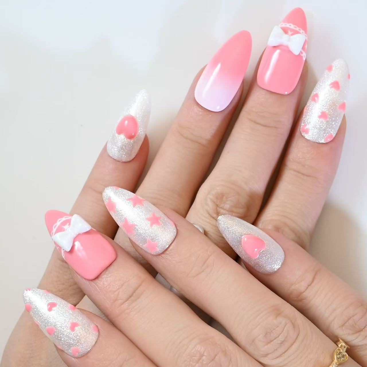 Sweet almond press-on nails with white bows, pearl decorations, and sparkly pink design