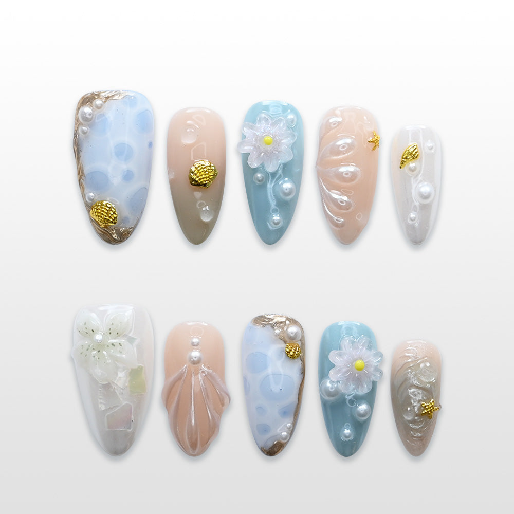 Blue and nude press-on nails with 3D seashell design, white flowers, and pearl accents