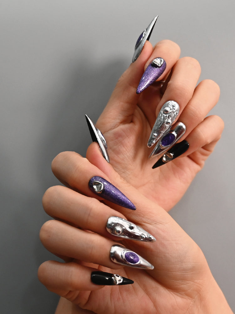 Handmade stiletto nails with chrome silver, black accents, and 3D orbs