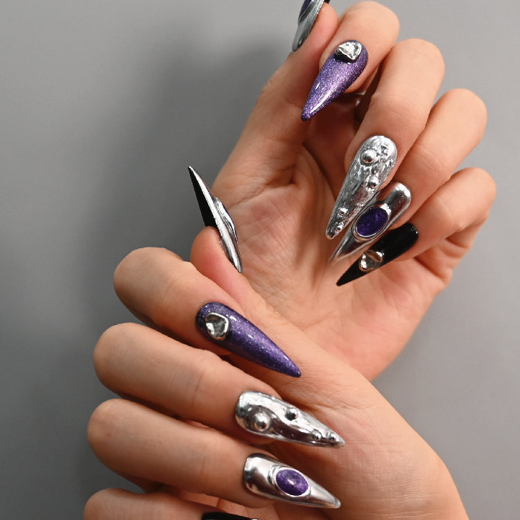 Handmade stiletto nails with chrome silver, black accents, and 3D orbs
