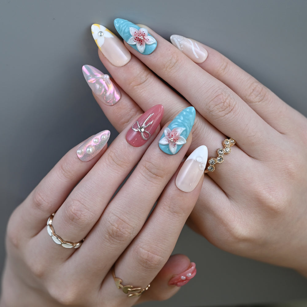 Ocean-inspired coral and turquoise nails with bow, pearl, and floral embellishments