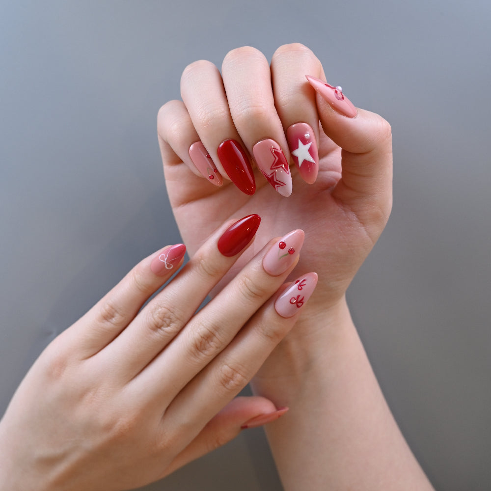 Romantic red and pink press-on nails featuring stars, bows, and fruit art
