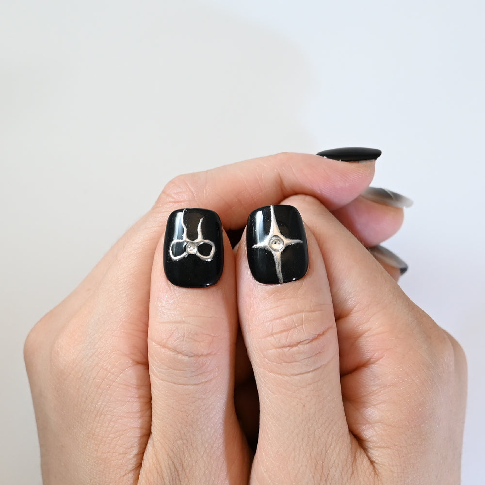 Elegant monochrome press-on nails with cat-eye shimmer, bow art, and feather details