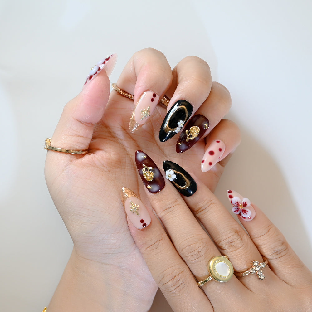 Luxury press-on nails with red and black mix, golden star embellishments, and 3D blossoms