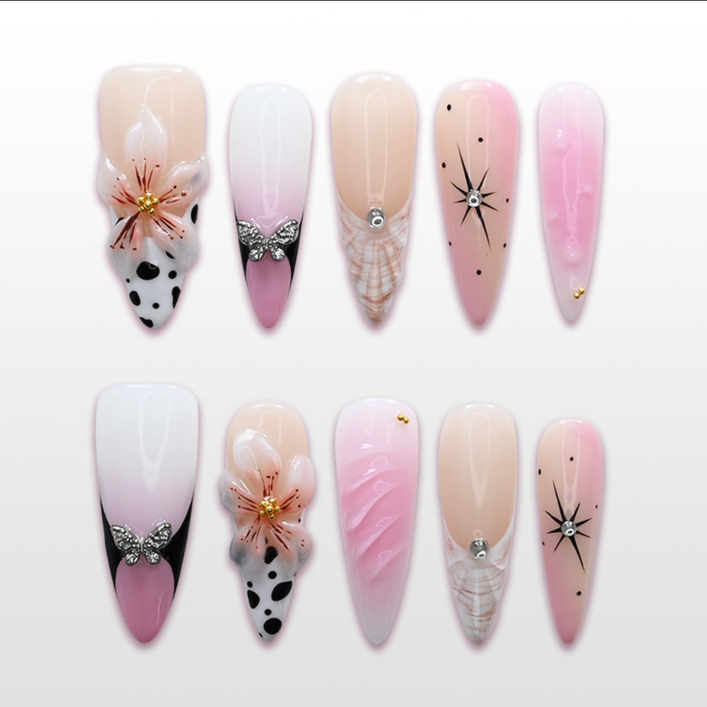 Pink and white ombre press-on nails with 3D flowers, butterfly charms, and starburst accents