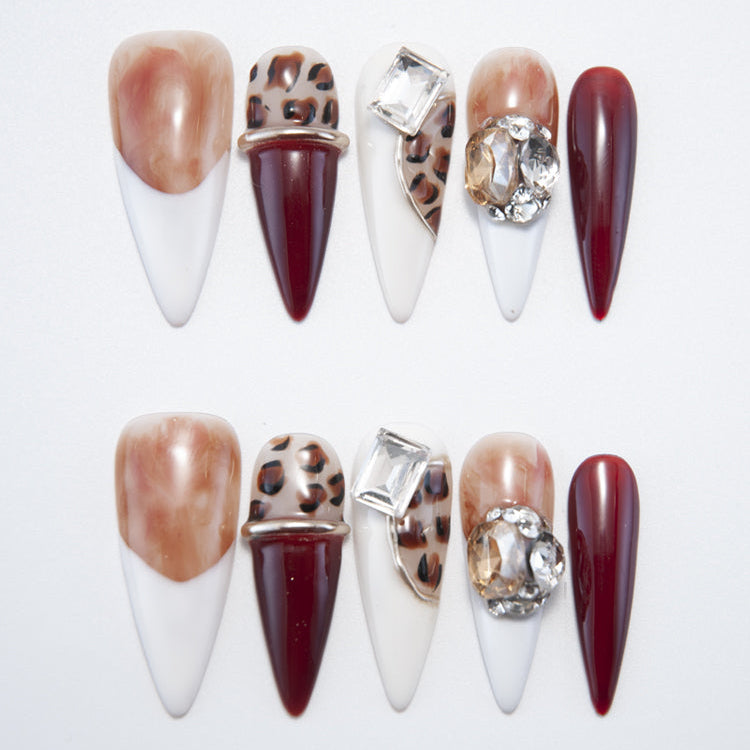 Long stiletto press-on nails with leopard print, burgundy tips, and gemstone accents