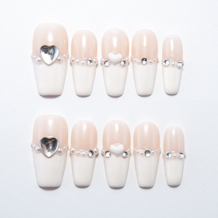 Nude and white French press-on nails with pearl and silver heart charms