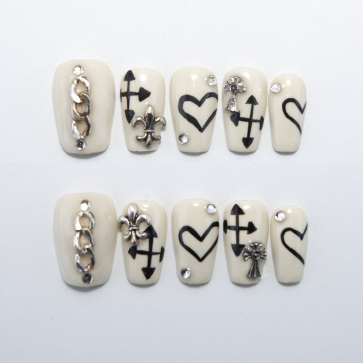 Cream white press-on nails with black heart and arrow symbols and silver chain accent