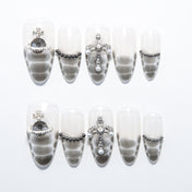 Silver-grey snake print press-on nails with gemstone cross and metallic bead accents