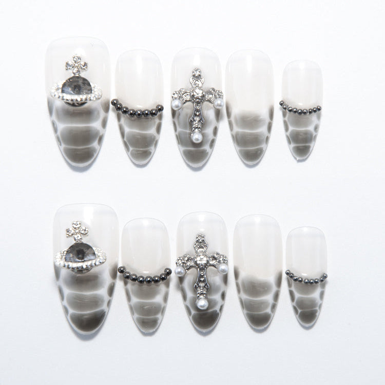 Silver-grey snake print press-on nails with gemstone cross and metallic bead accents