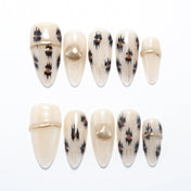 Beige press-on nails with black and brown leopard print and gold metallic accents
