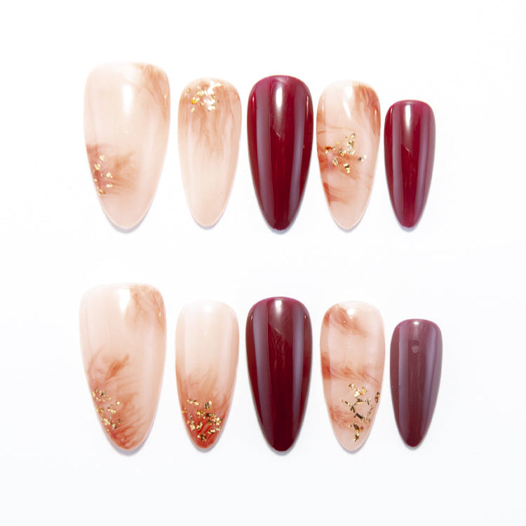 Elegant burgundy press-on nails with marble swirl design and gold flakes