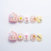 Short square press-on nails with pink cartoon character, daisy flowers, and pastel accents