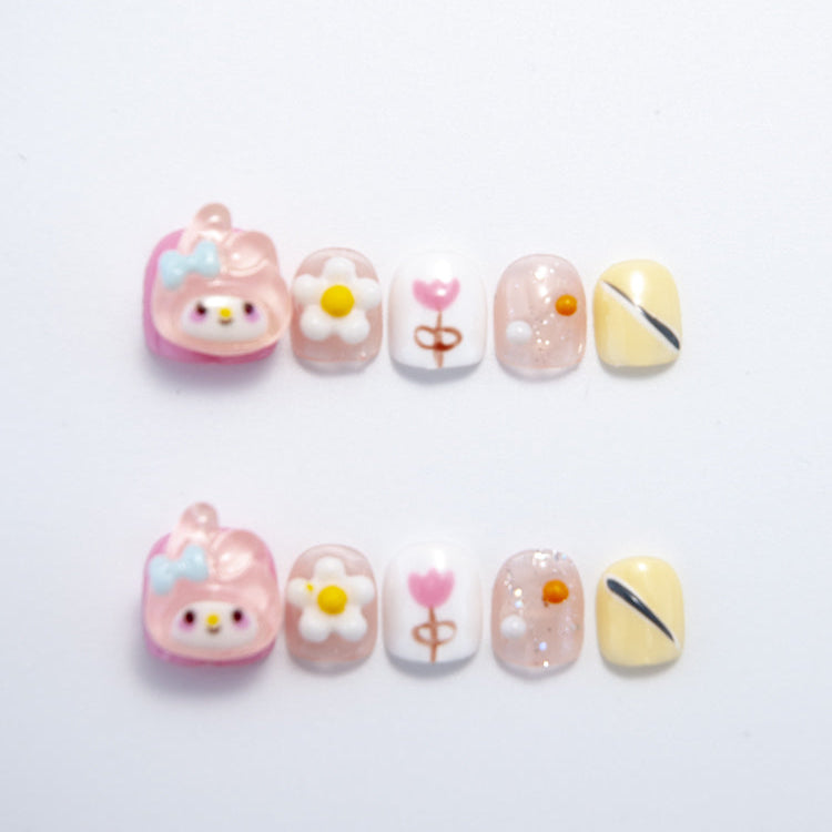 Short square press-on nails with pink cartoon character, daisy flowers, and pastel accents