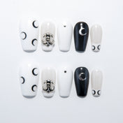 Black and white press-on nails with crescent moon designs and silver metal charm