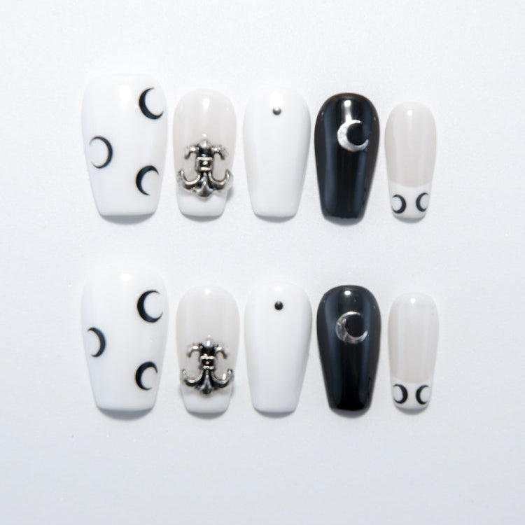 Black and white press-on nails with crescent moon designs and silver metal charm